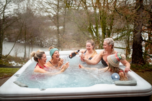 Hen party celebrate with champagne in an outdoor hot tub