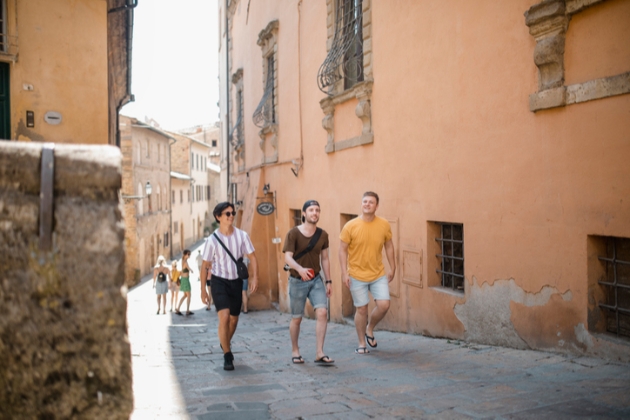 Three young men walk through a historic european town
