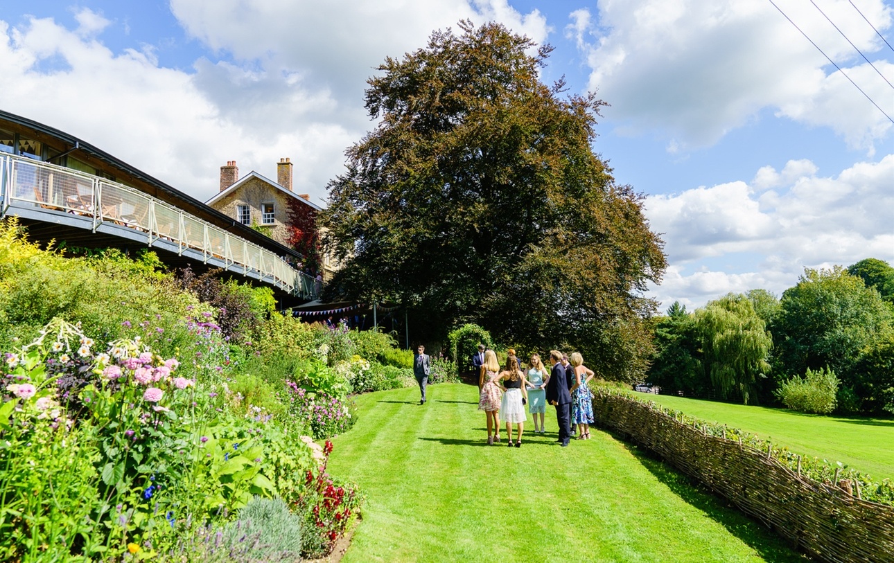 Outside view of Somerset wedding venue The Longhouse with gardens and wedding guests