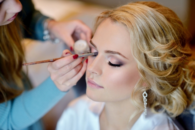 A beautiful bride having her makeup applied by a makeup artist