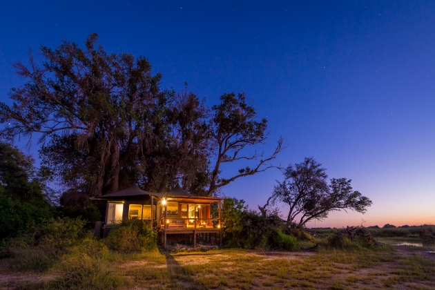 safari lodge at night lit by camp lights looking out on to bush