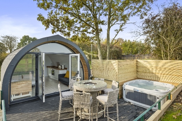 pod with fenced off space hot tub and tables and chairs outside 