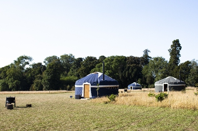 yurt in field with fire pit with other yurts in background
