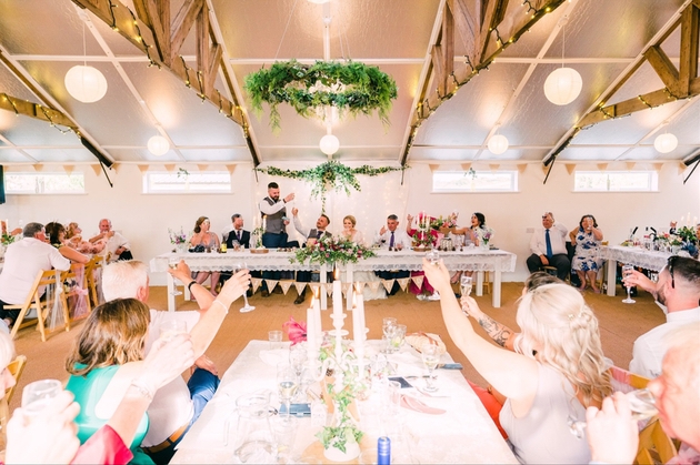 Newlyweds and guests making a toast at The Barn at Cott Farm wedding venue in Somerset.