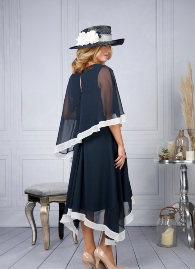 Mother of the bride in navy and cream outfit with hat.