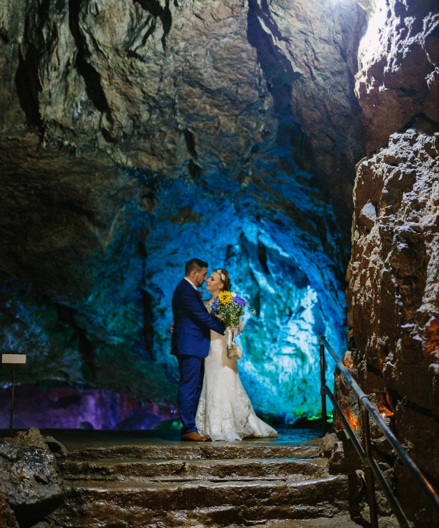 Bride and groom together in Wookey Hole caves illuminated in blue