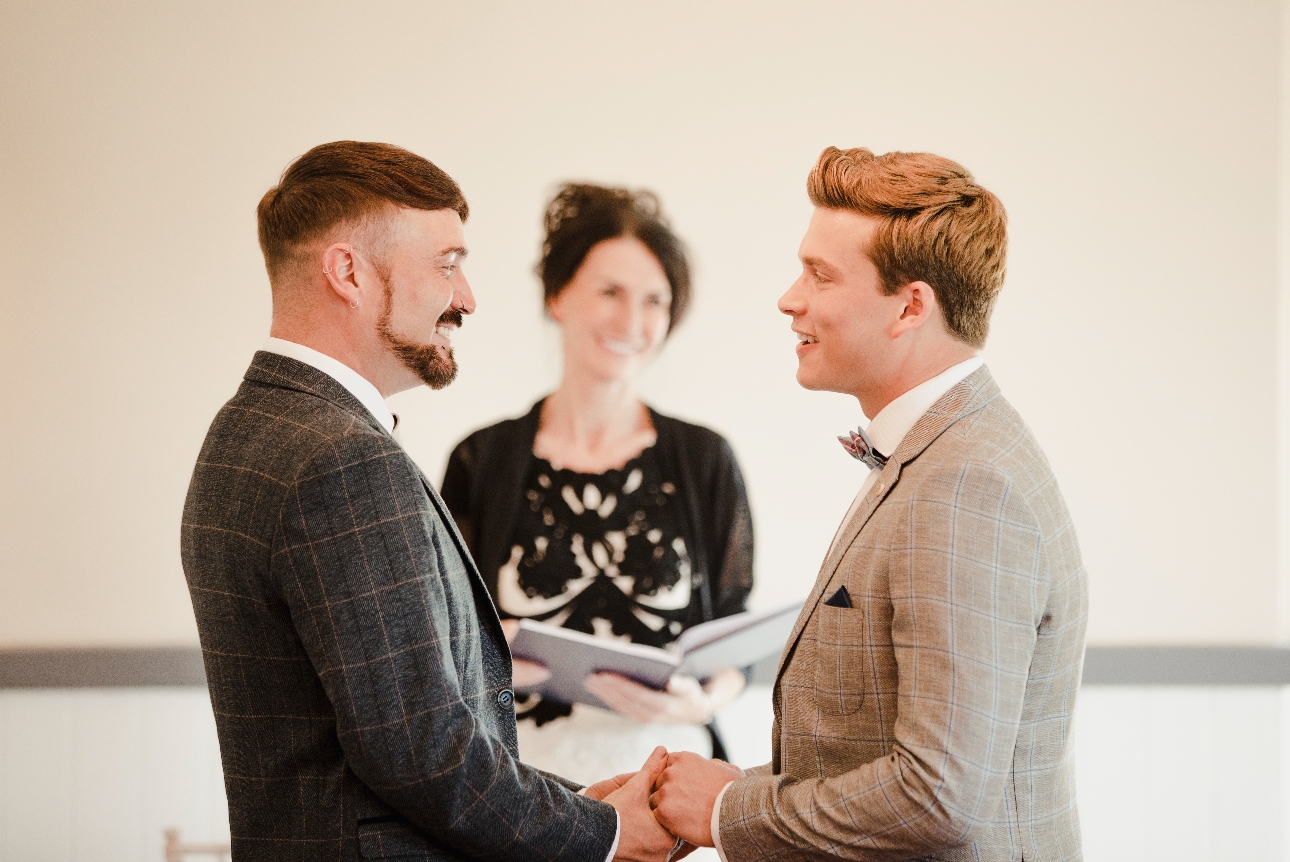 two men standing in front of a celebrant looking to tie the knot