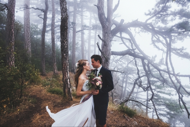 Bride and groom in the woods on a misty day