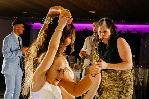 Lucy Harvey saxophonist entertaining guests on the dancefloor at a wedding reception 