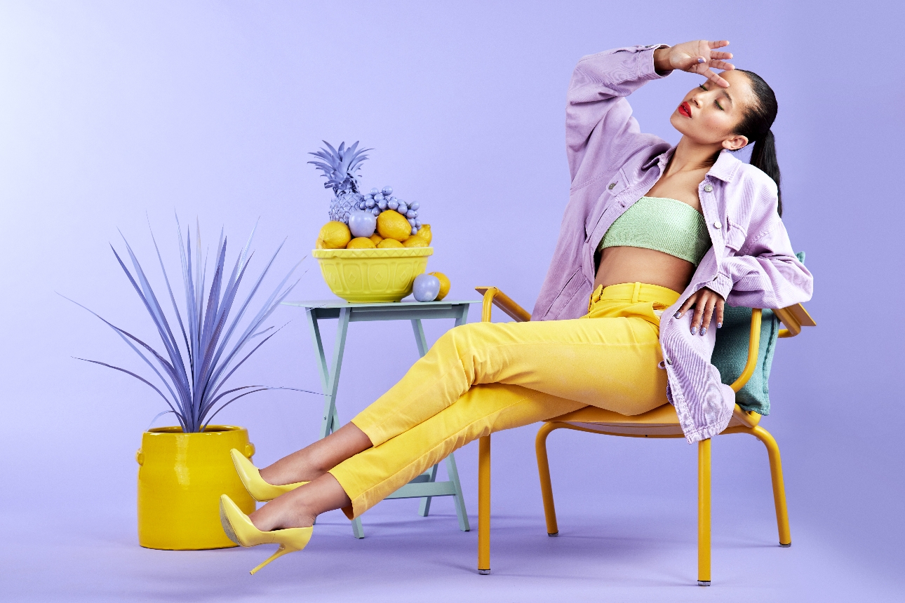 woman in yellow trousers green top and purple shirt sat on a chair