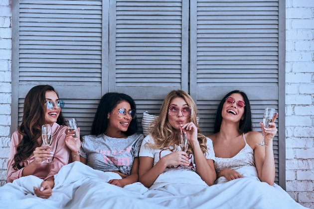 Four girls sitting in bed laughing
