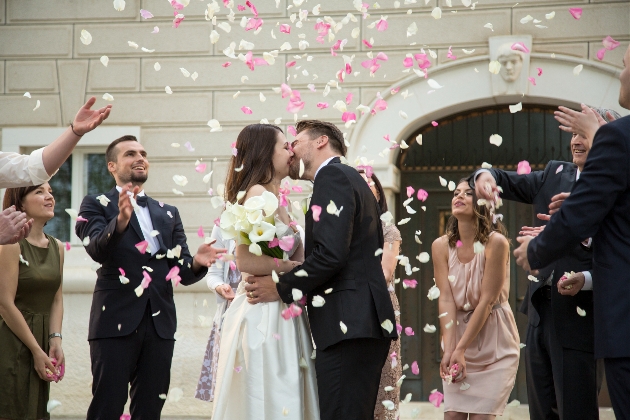 Couple kissing while their guests throw confetti over them