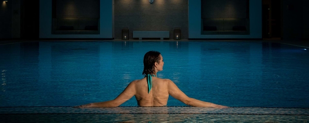 Woman in a swimming pool relaxing against the edge