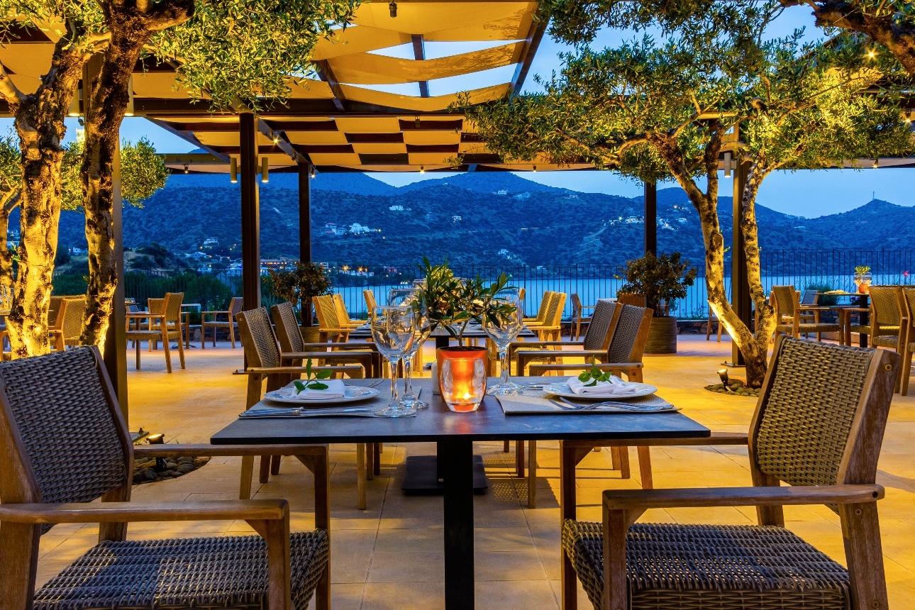 tables al fresco on covered terraced at night sea and mountain views