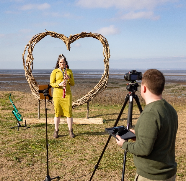 Lucy Harvey being filmed for her video outside with heart backdrop
