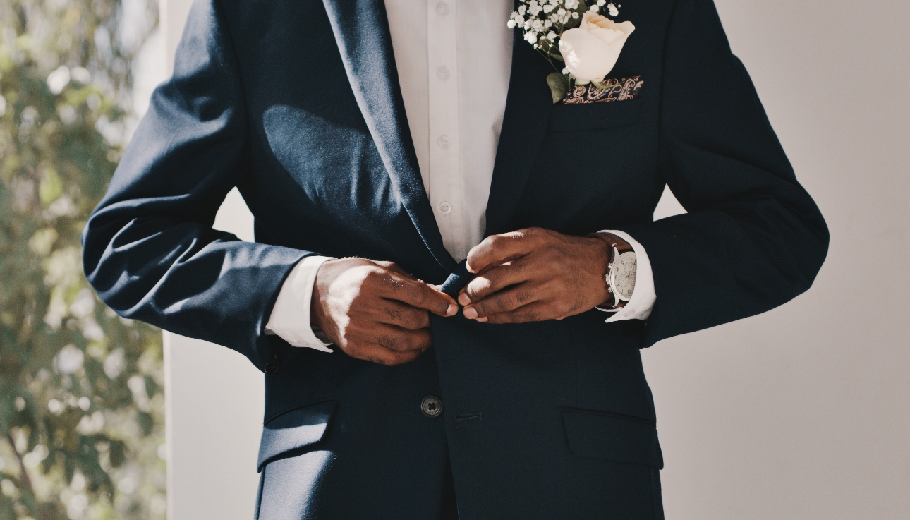 groom wearing a watching buttoning up his suit