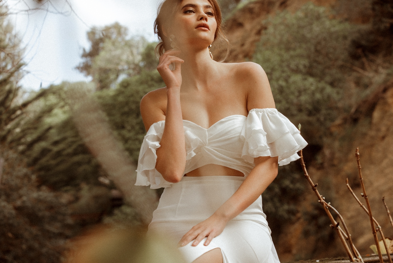 model in white crop top off shoulder frill sleeves and wrap over detail