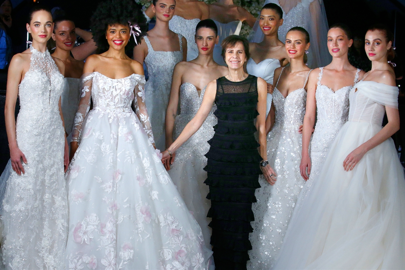 group of models all in wedding dresses designer in middle on black