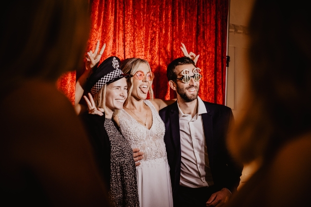 Three people enjoying themselves with props at a wedding in the photo booth