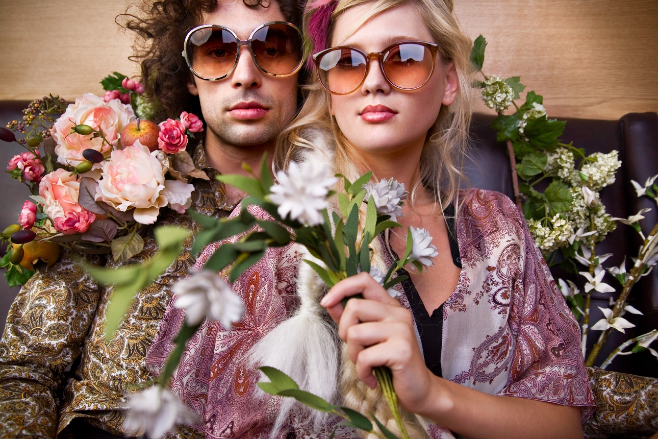 couple in 70s fashion and sunglasses holding flowers