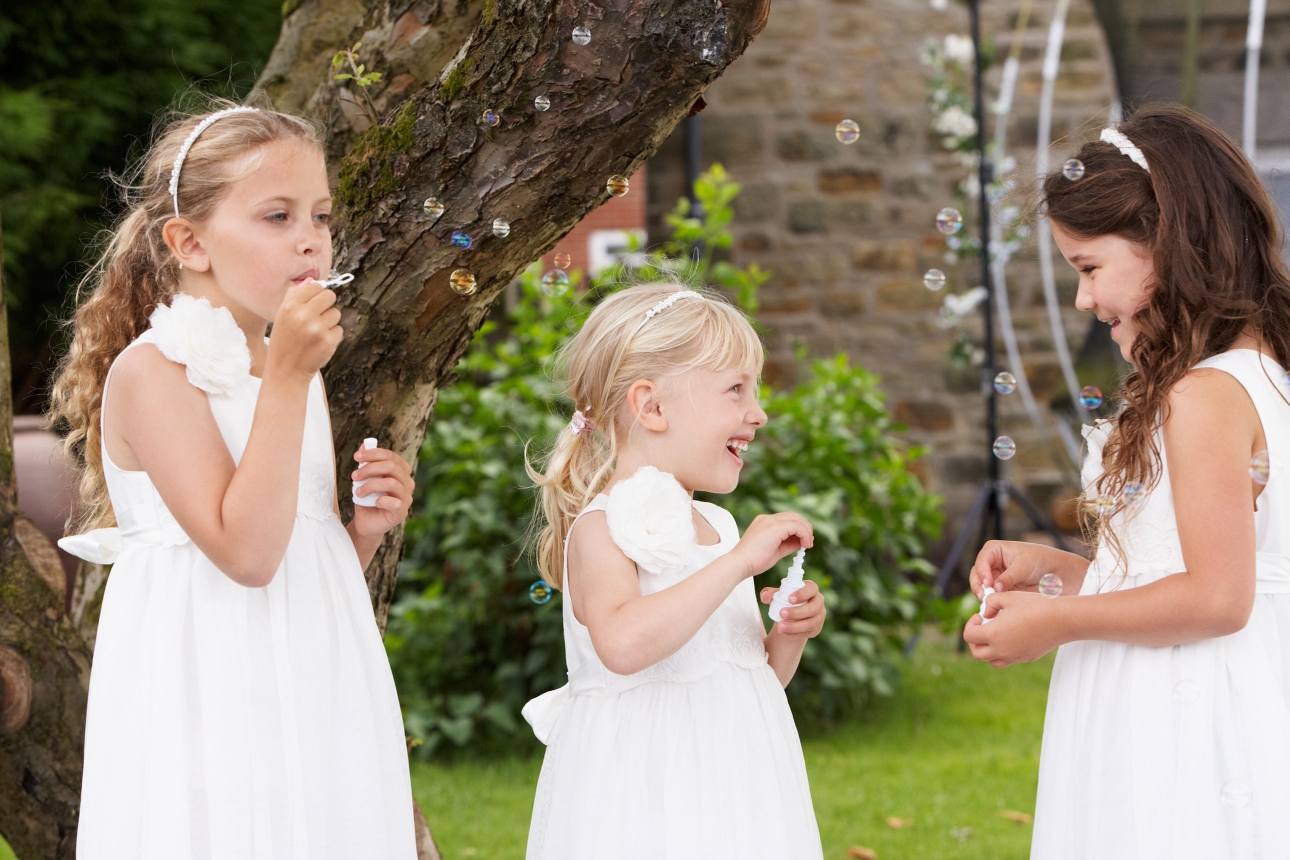three girls in bridemaid dresses blowing bubbles
