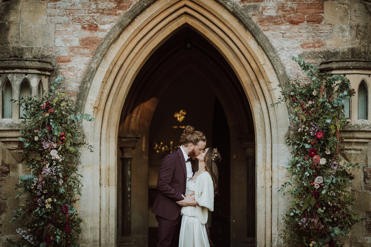 bride and groom kissing in archway of Bishop's Palace Wells