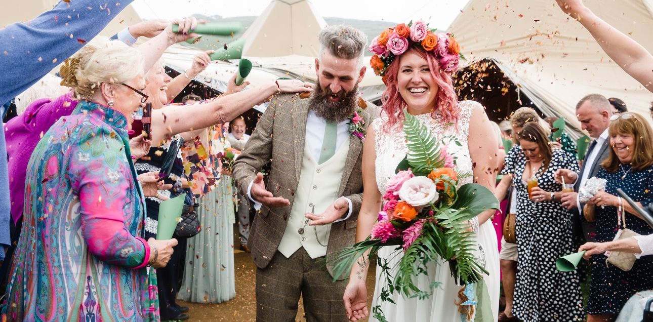 couple walking through a confetti throw with tipis and more guests in the background