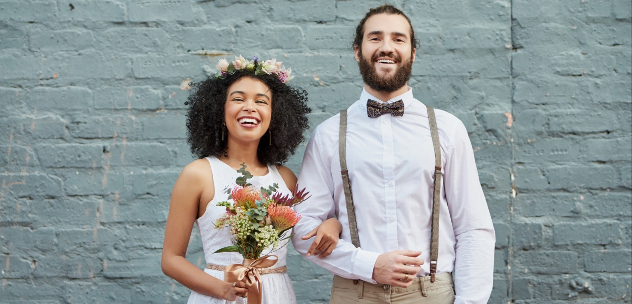Bride and groom posing in front of grey brick wall rustic vibes
