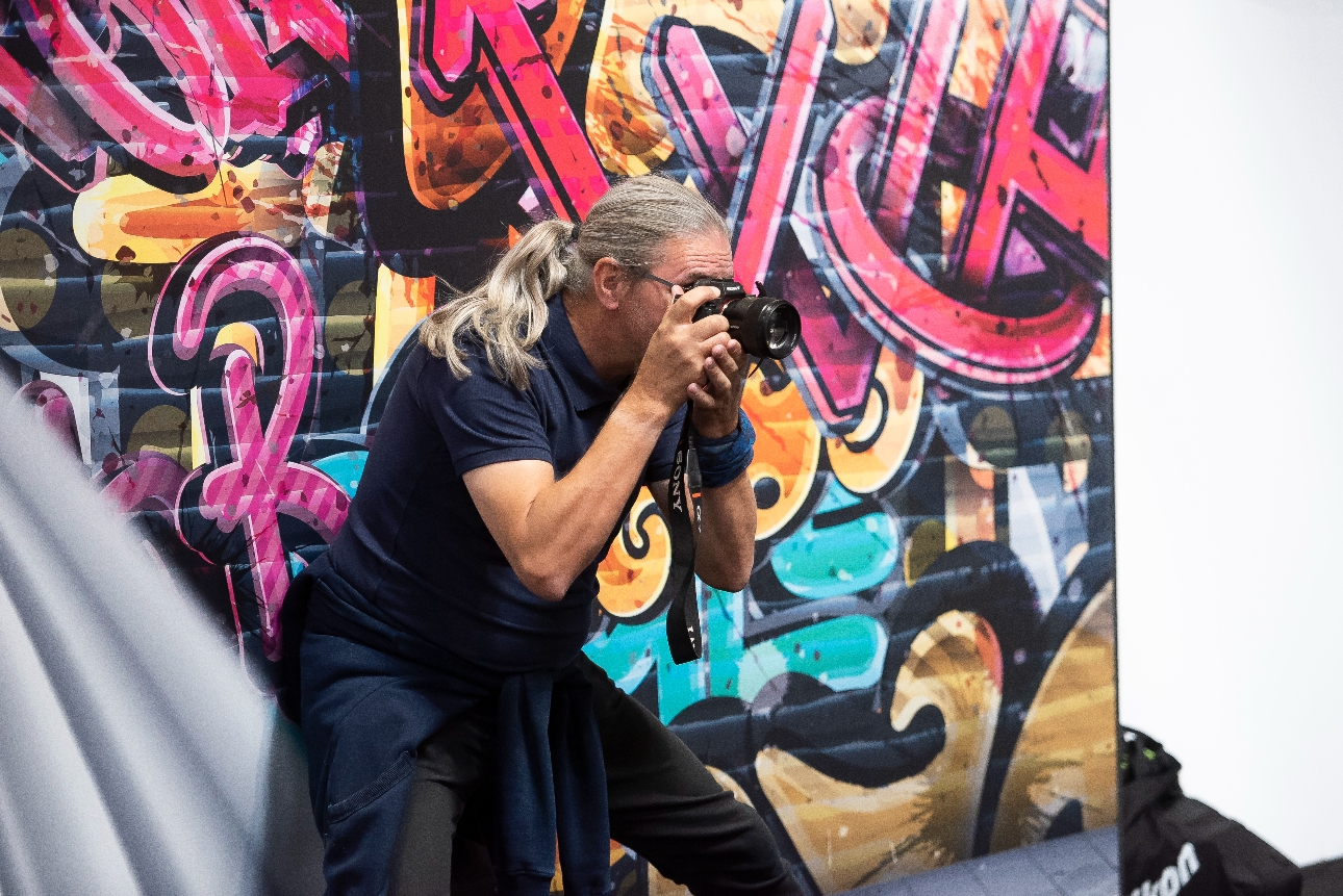 man holding camera against a graffiti backdrop