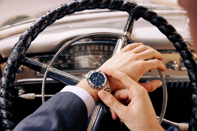 A man sitting in a car admiring a silver watch on his wrist