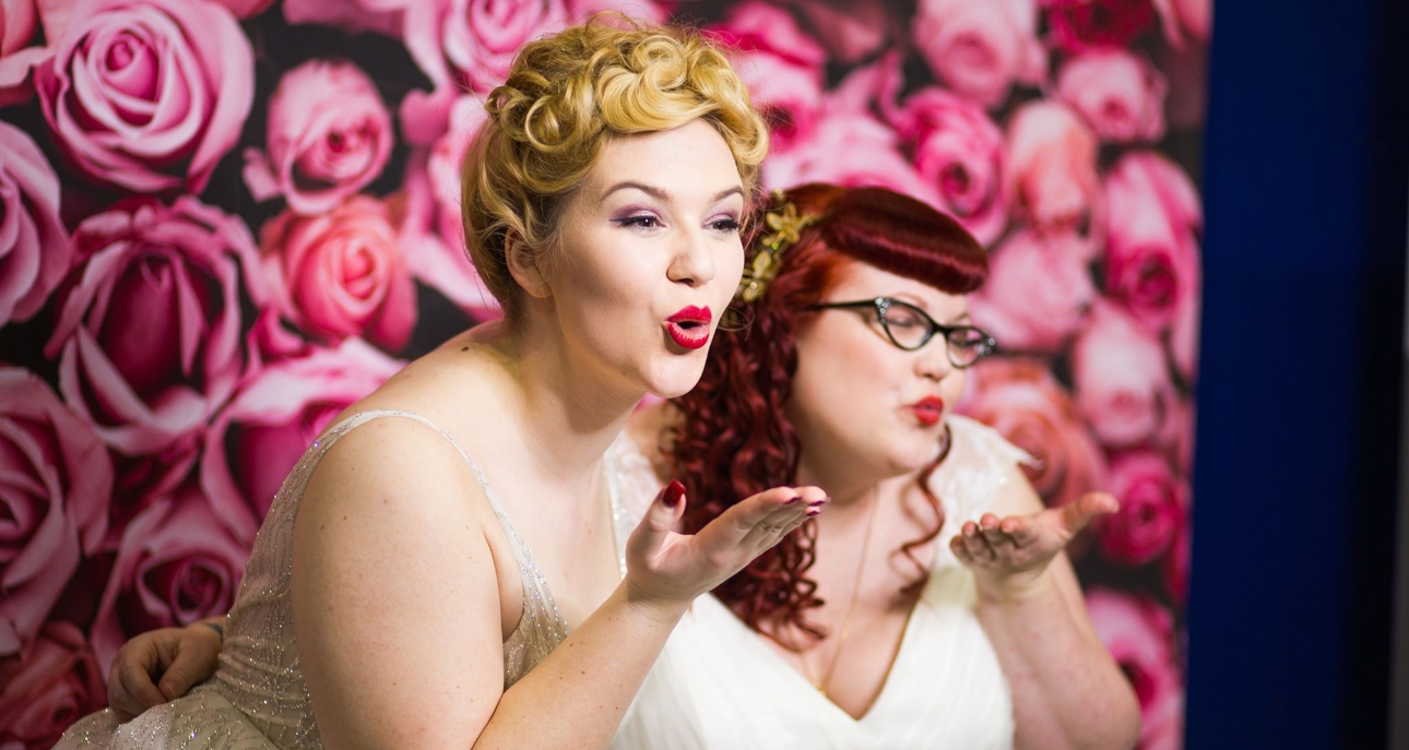 two brides blowing kisses in photo booth