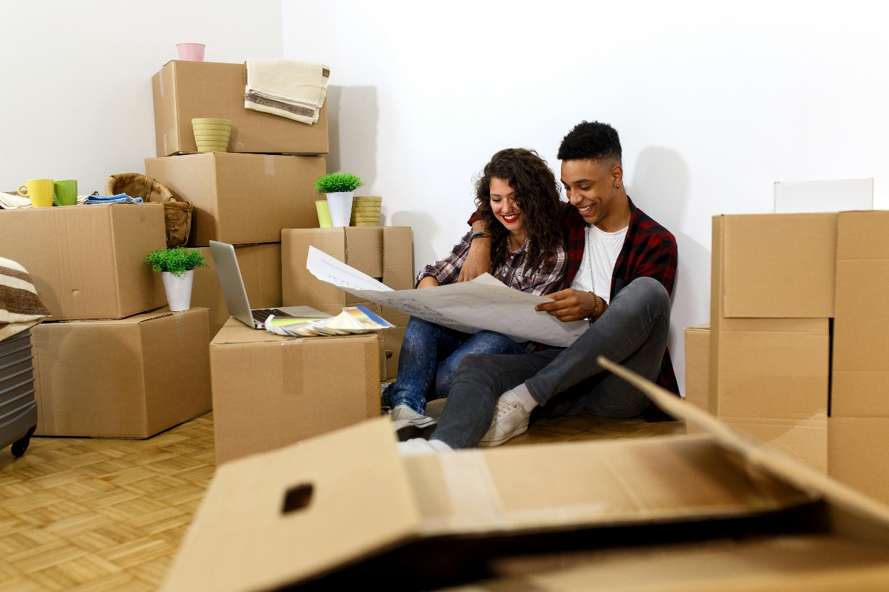 couple sat on floor surrounded by moving boxes